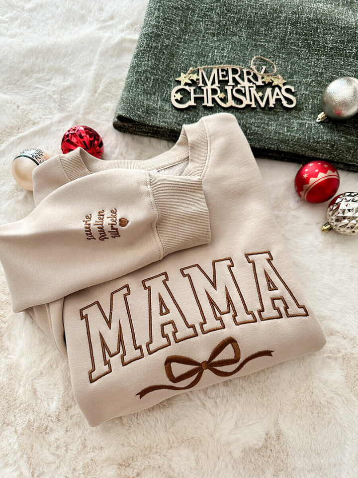 Zoom sur la broderie nœud élégante du pull de Noël femme MerryMom. Parfait pour les fêtes hivernales et le confort.