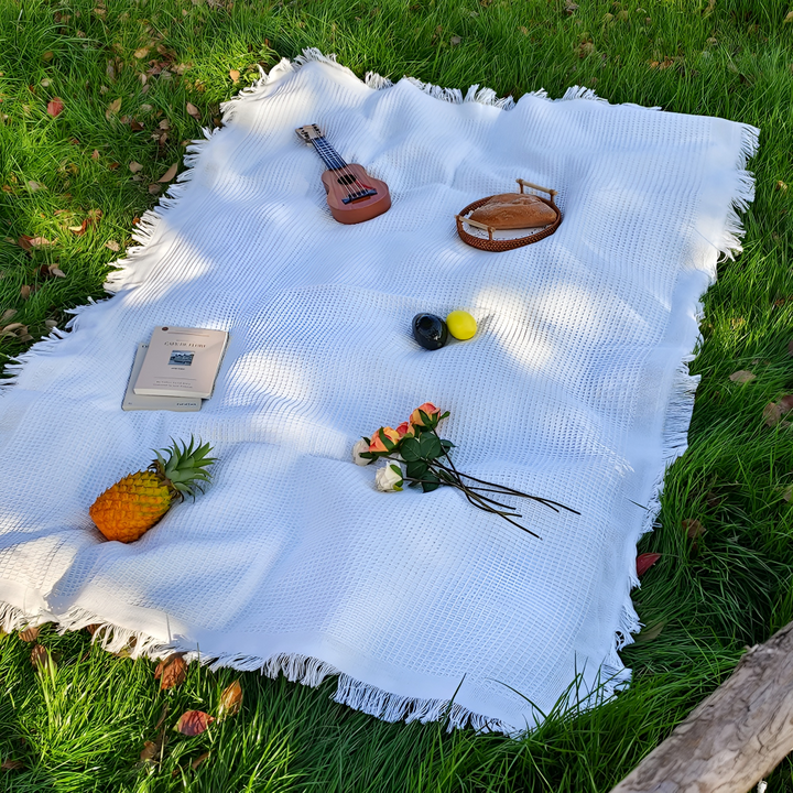 Couverture de pique-nique bohème blanche avec pompons, idéale pour le jardin et l'extérieur.
