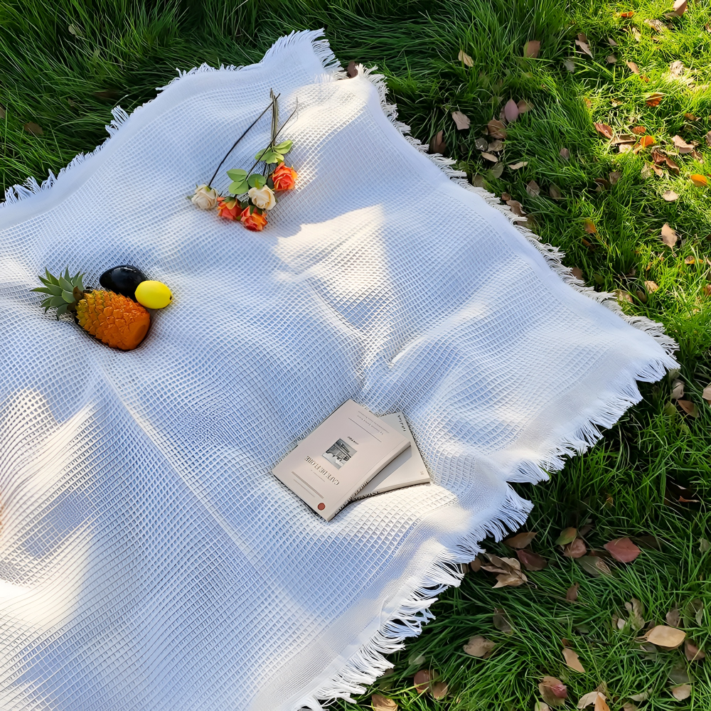 Magnifique couverture de pique-nique blanche bohème avec pompons, parfaite pour un esprit libre en extérieur.