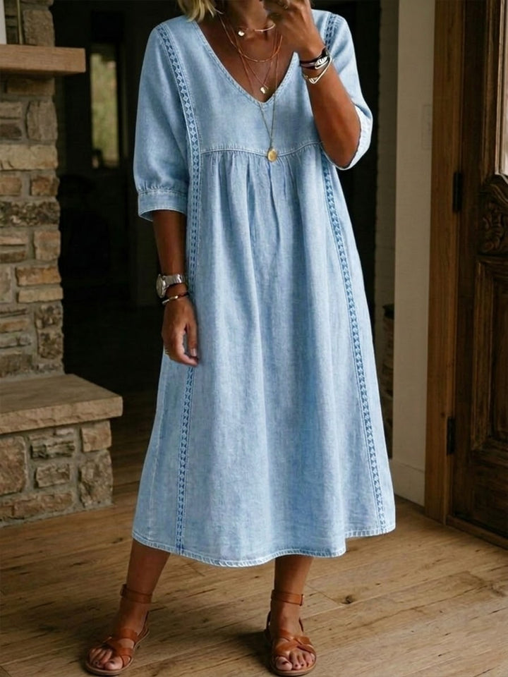 Robe femme fluide en denim bleu, col V et dentelle raffinée. Look élégant et décontracté, parfaite pour l'été.