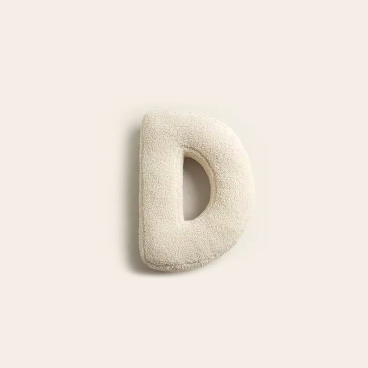 Coussin décoratif lettre E, touche design pour un salon élégant.