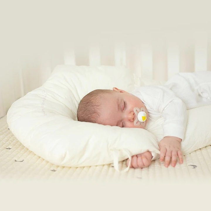 Bébé dormant paisiblement sur son coussin sommeil hypoallergénique, garantissant confort, sécurité et repos profond.