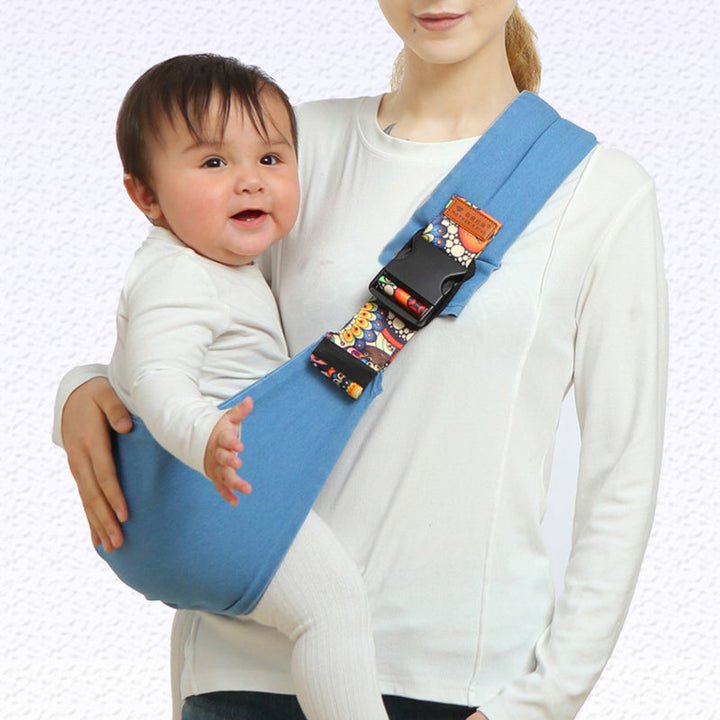 Maman portant bébé en porte-bébé ergonomique, mains libres, pour une promenade en ville.