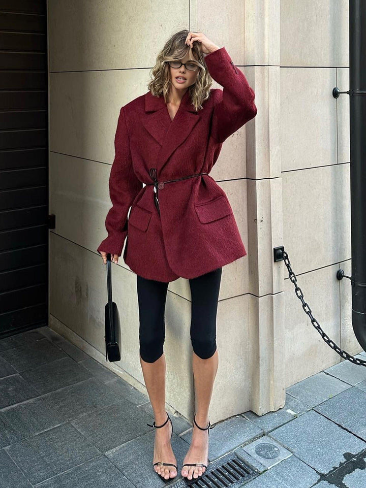 Blazer femme rouge automne, coupe ajustée et ceinture, pour un look féminin, élégant et professionnel. Vêtement de bureau chic.