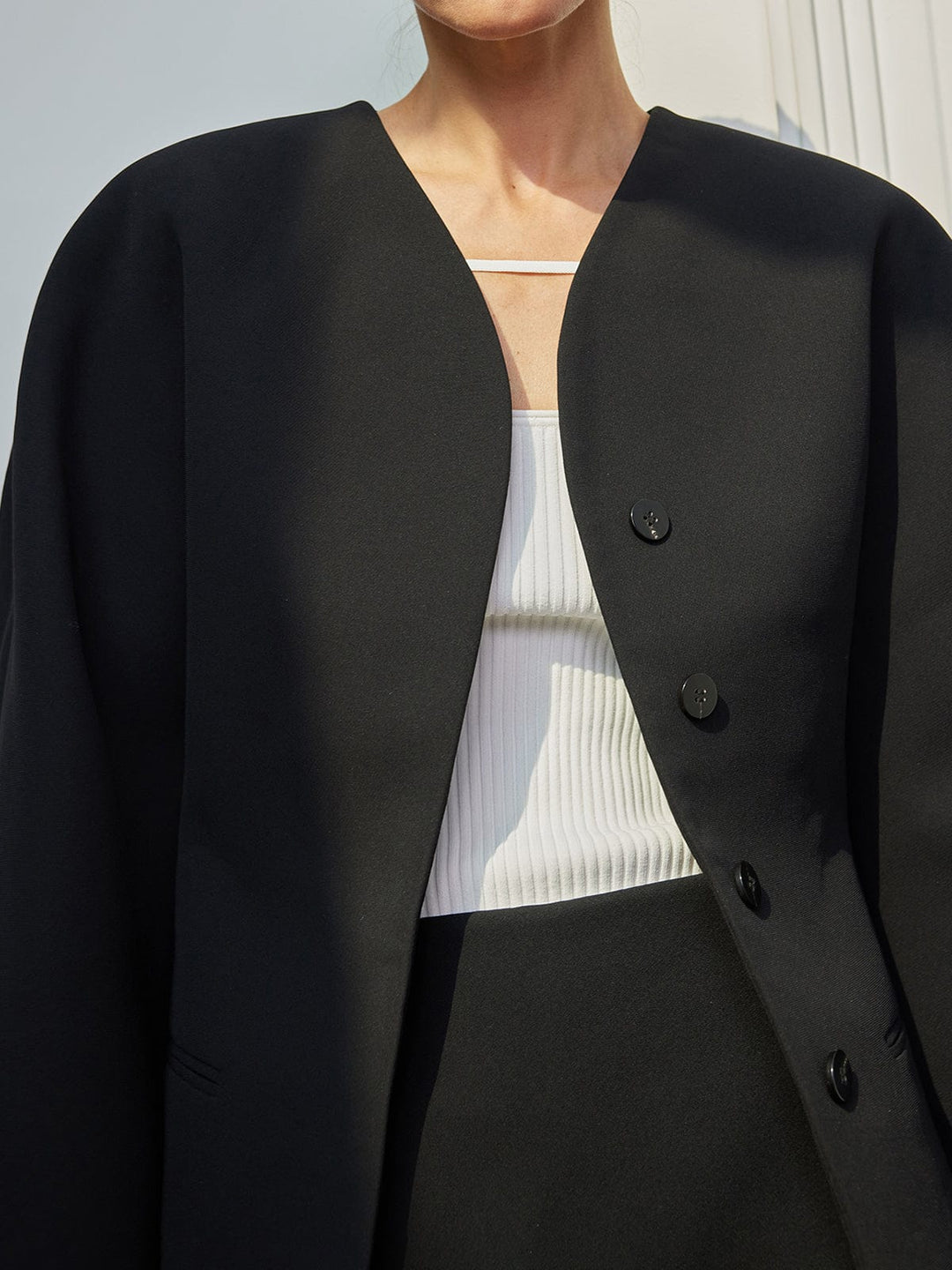 Blazer femme noir élégant avec coupe droite, sans revers. Veste moderne et chic avec boutons décoratifs.