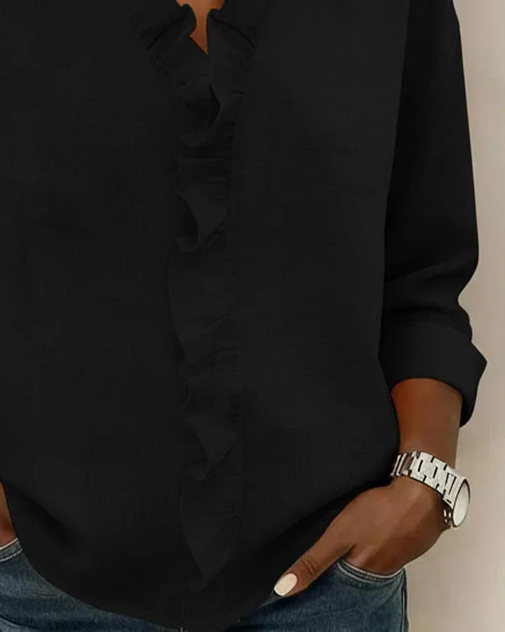 Blouse femme chic noire avec volants subtils, col V et manches longues. Idéale pour une tenue de bureau moderne.