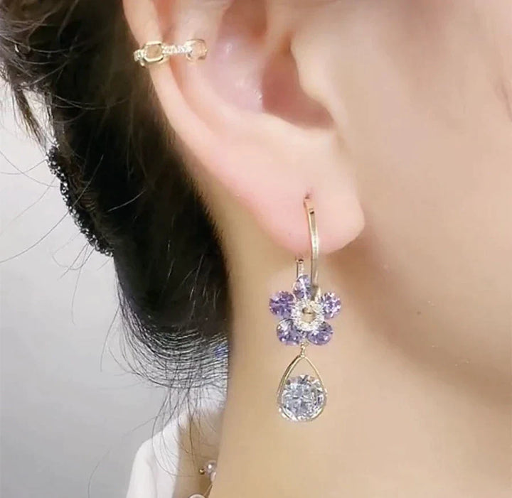 Boucles d'oreilles pendantes femme avec motif floral en cristal, nuances bleu et violet.