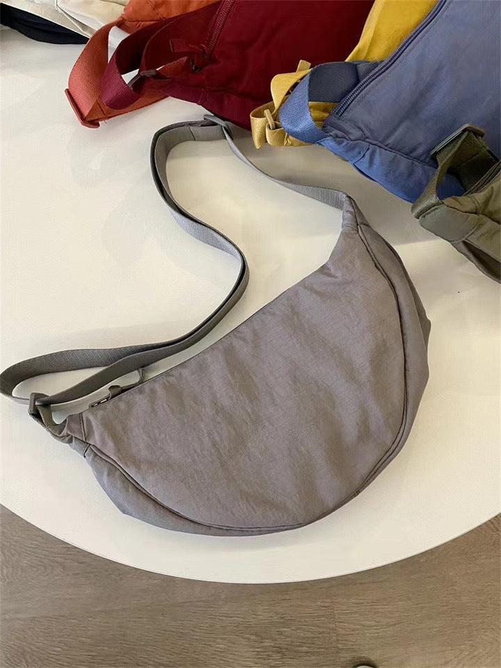 Sac bandoulière femme, porté sur l'épaule. Compact, léger, et chic avec sa forme arrondie distinctive.