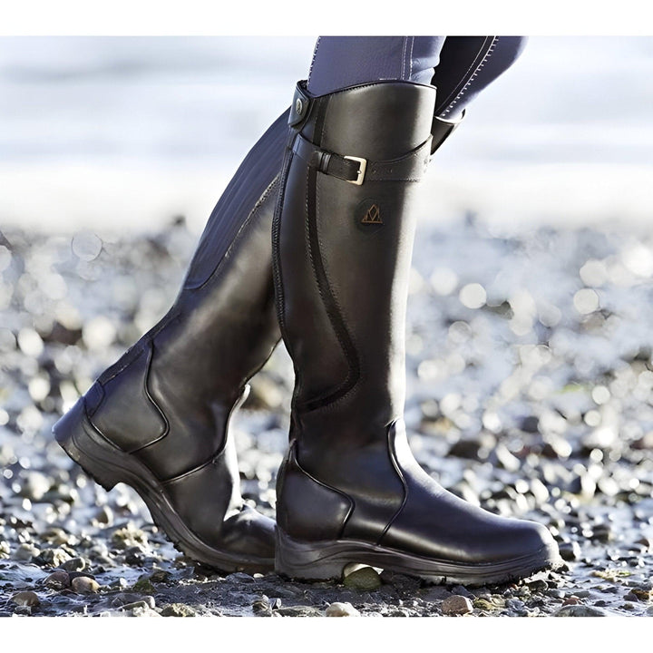Femme portant des bottes imperméables polyvalentes, parfaites pour la marche en ville ou en nature, alliant style et confort.