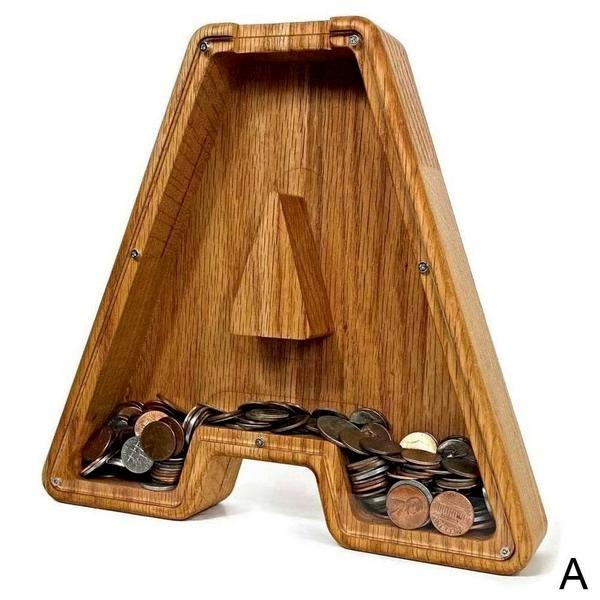 Vue rapprochée de pièces de monnaie tombant dans une tirelire alphabet en bois.