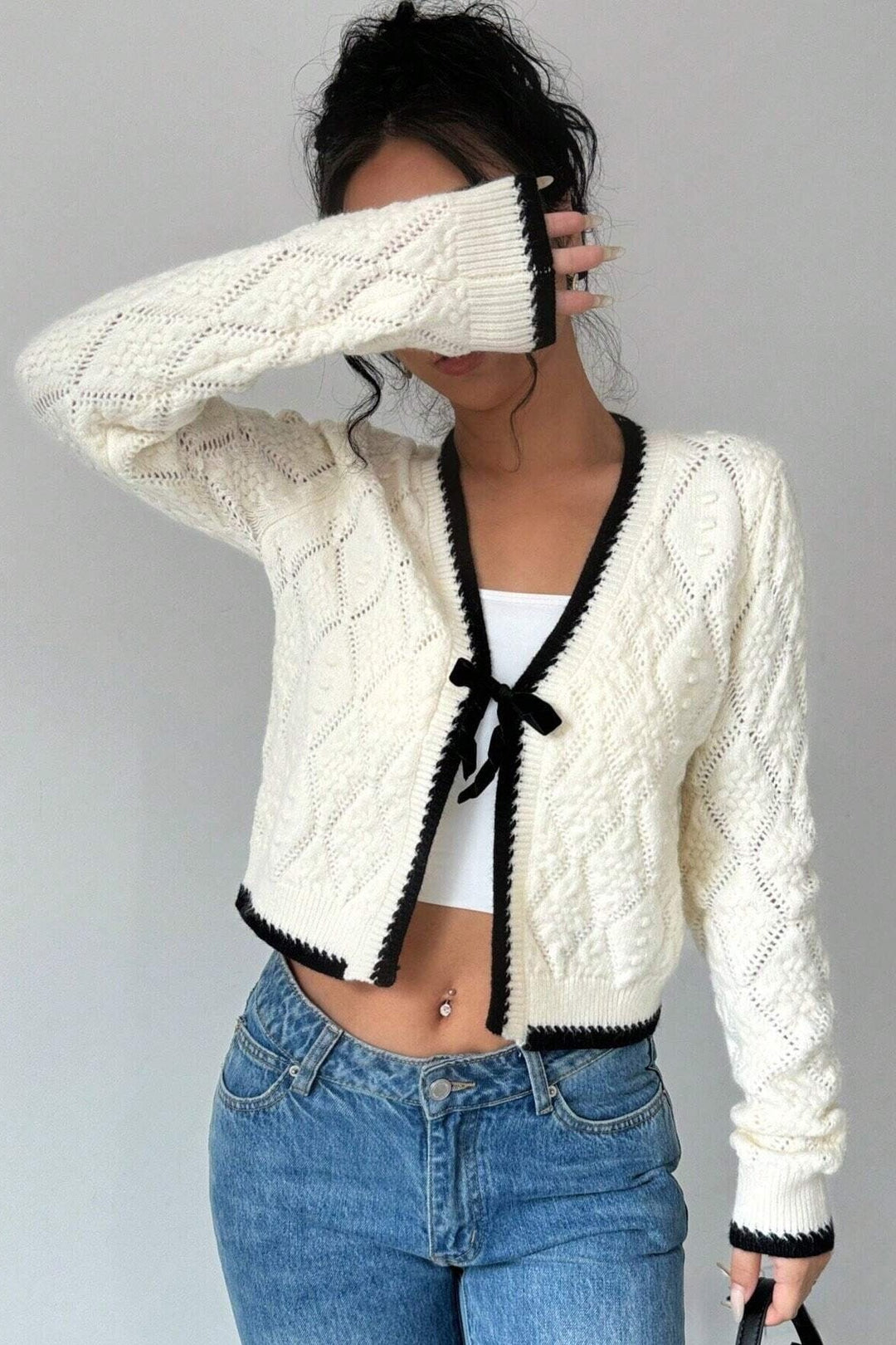 Cardigan ajouré blanc léger pour femme, avec nœud au col et bordures foncées contrastantes. Look chic.