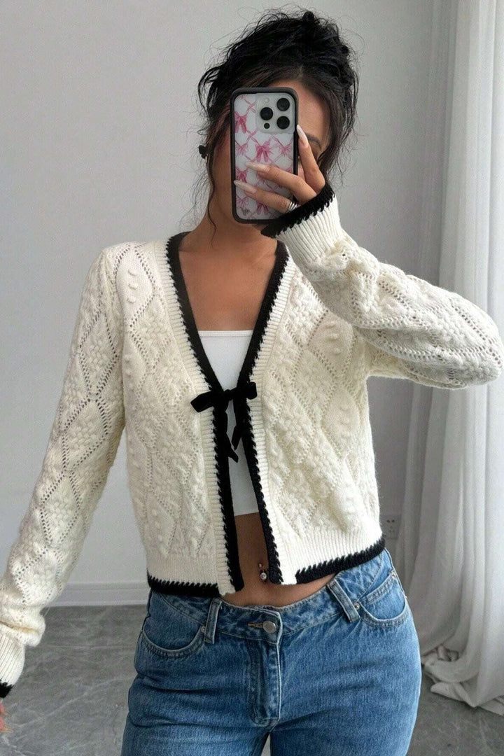 Cardigan court ajouré blanc pour femme avec nœud délicat et bordures contrastées. Idéal printemps/automne.