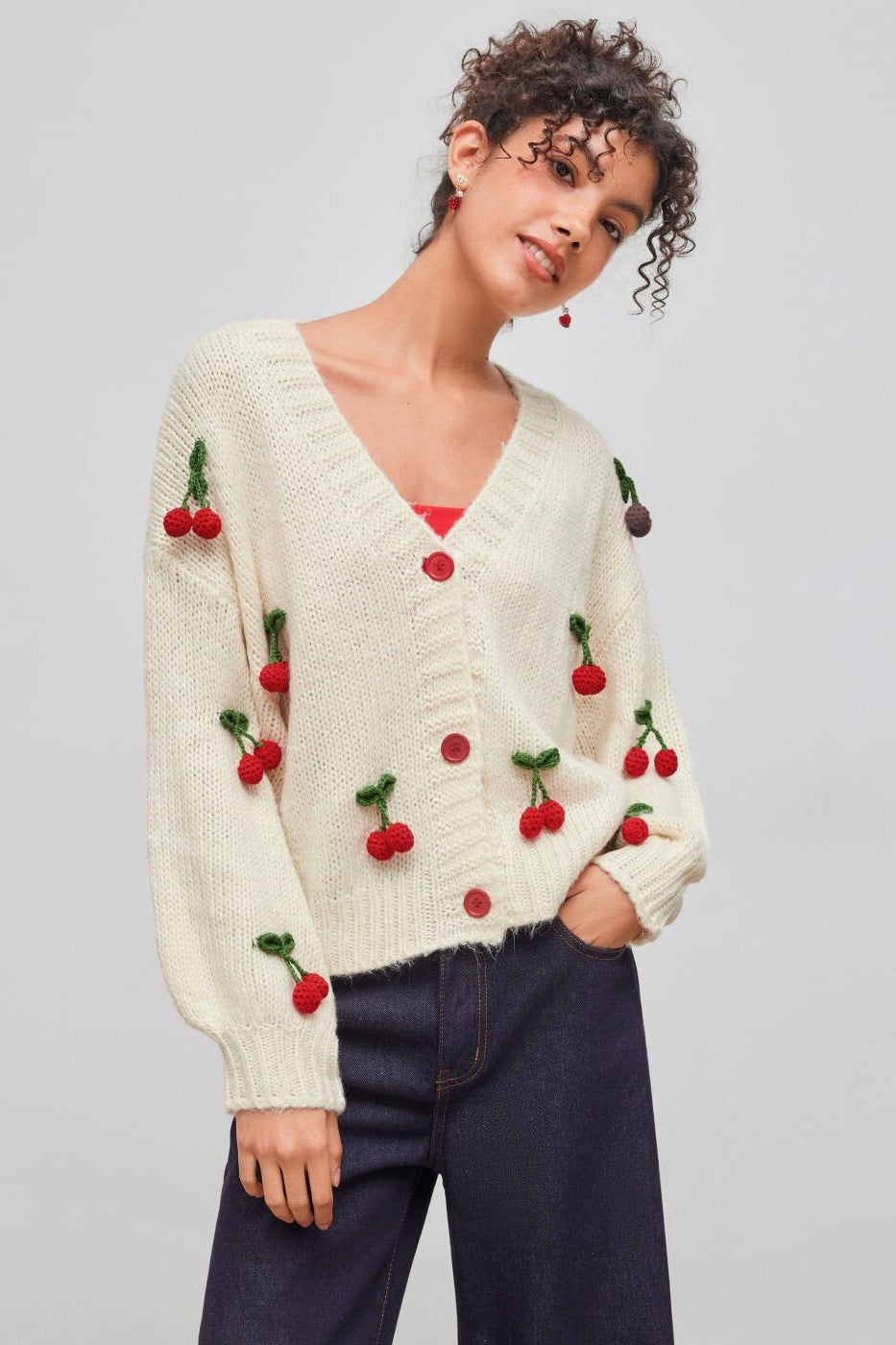 Pull ample femme en maille, col en V, avec applications cerises. Parfait pour un look décontracté chic.