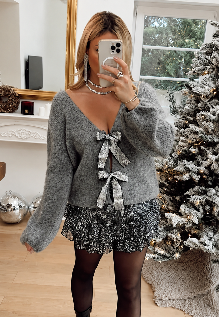 Cardigan élégant femme, col en V, ornements nœuds brillants. Mode hiver, tenue de soirée ou fête.