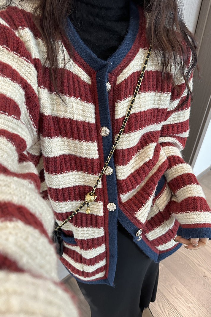 Femme portant un cardigan à rayures contrastantes, boutons métalliques, créant une tenue de superposition chic et moderne.