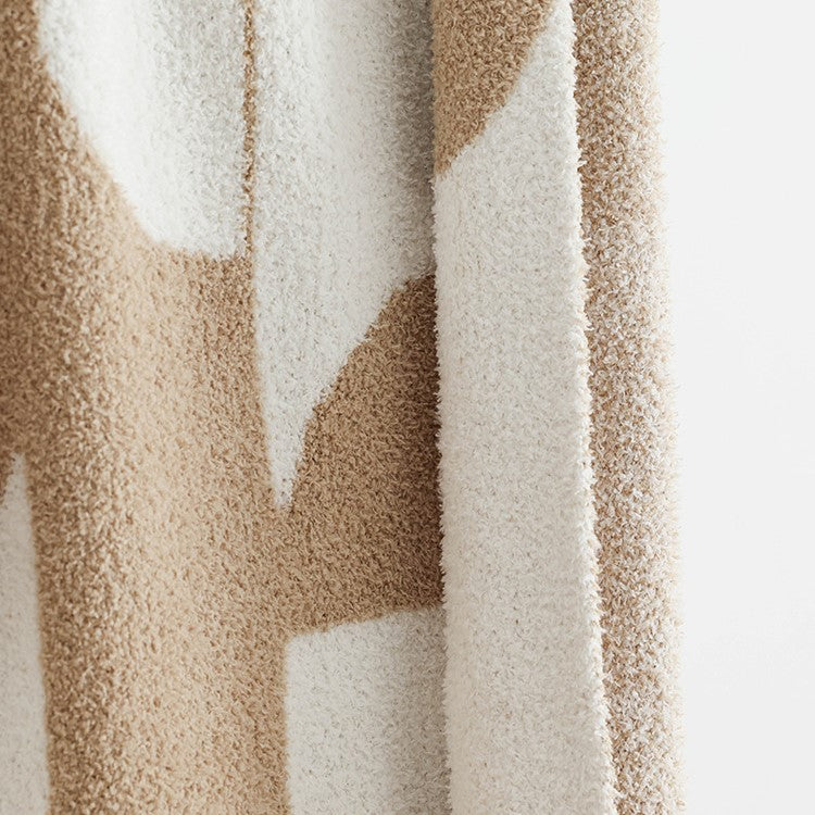 Couverture tricotée douce à motif géométrique, idéale pour apporter chaleur et style dans un salon ou une chambre.