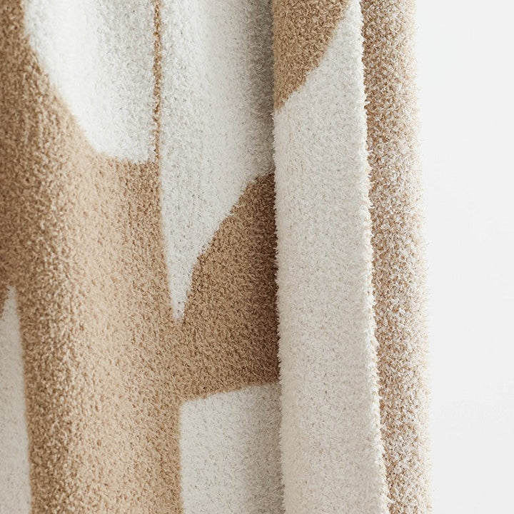 Couverture tricotée douce à motif géométrique, idéale pour apporter chaleur et style dans un salon ou une chambre.