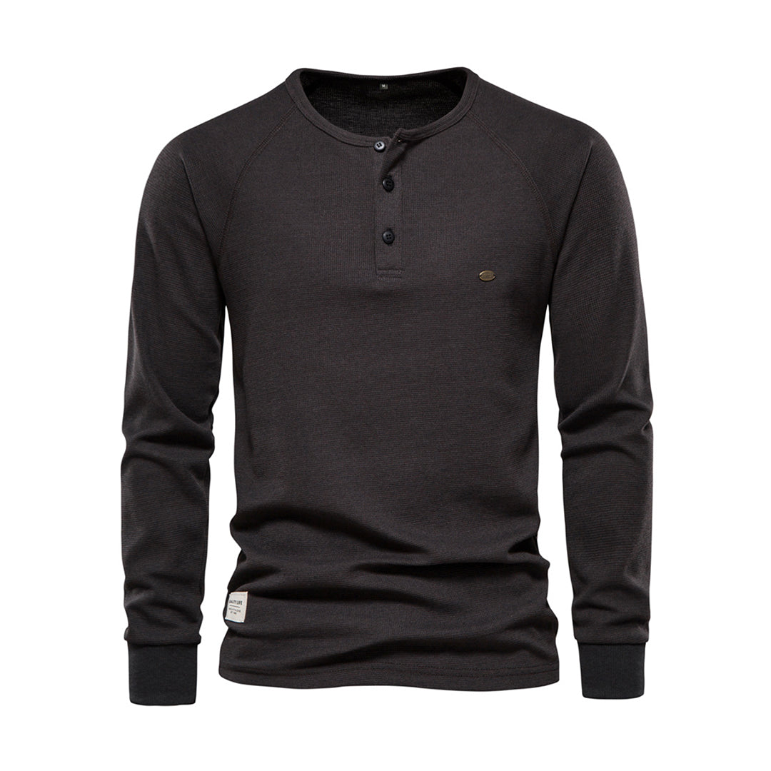 Gros plan sur les boutons et le col d'un t-shirt Henley homme à manches longues. Détail du vêtement casual.
