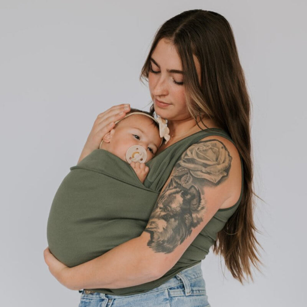 Parent souriant portant son bébé dans un porte-bébé T-Shirt pratique et ergonomique, mains libres.