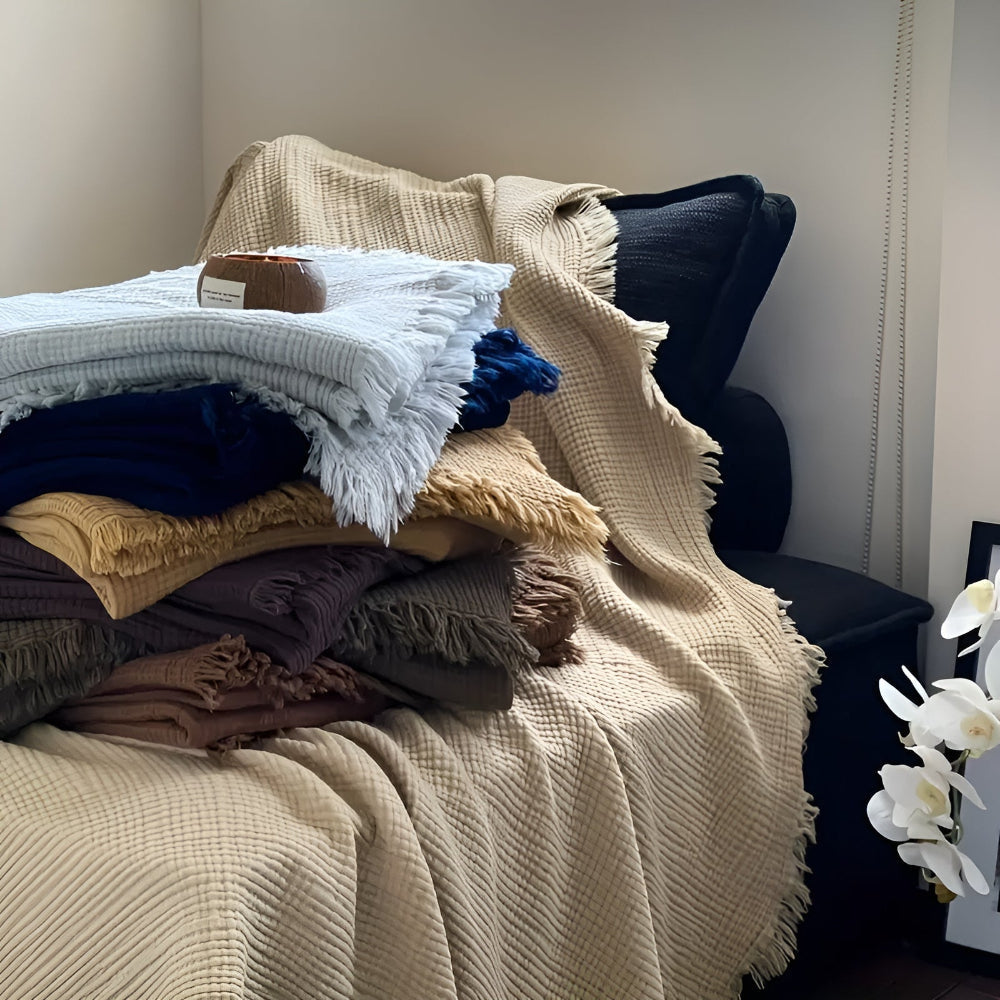 Gros plan sur les franges du plaid en coton gaufré, accentuant la texture douce et le style de ce jeté.