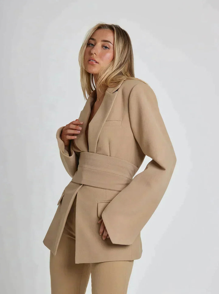 Détail du blazer Zanda beige pour femme, avec ceinture cravate soulignant la taille, style chic et moderne.