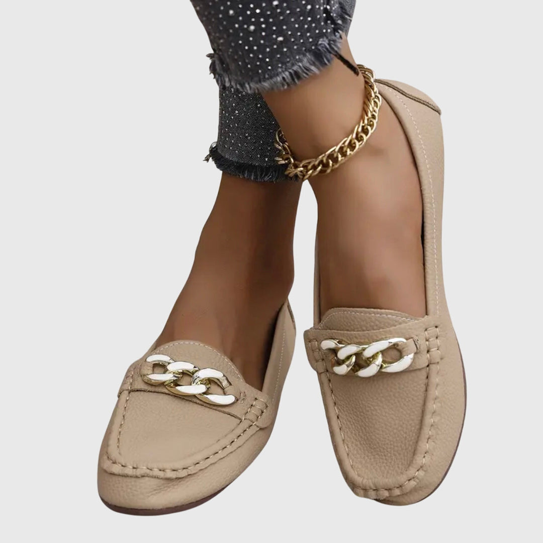 Élégants mocassins femme noirs avec chaîne métallique sur le dessus. Modèle bout rond, parfait pour toute occasion.