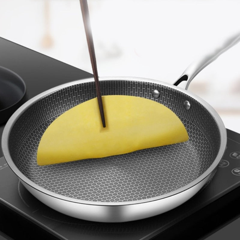 Poêle à frire SteelCook 28 cm en acier inoxydable sur une plaque à induction, pour une cuisson rapide.