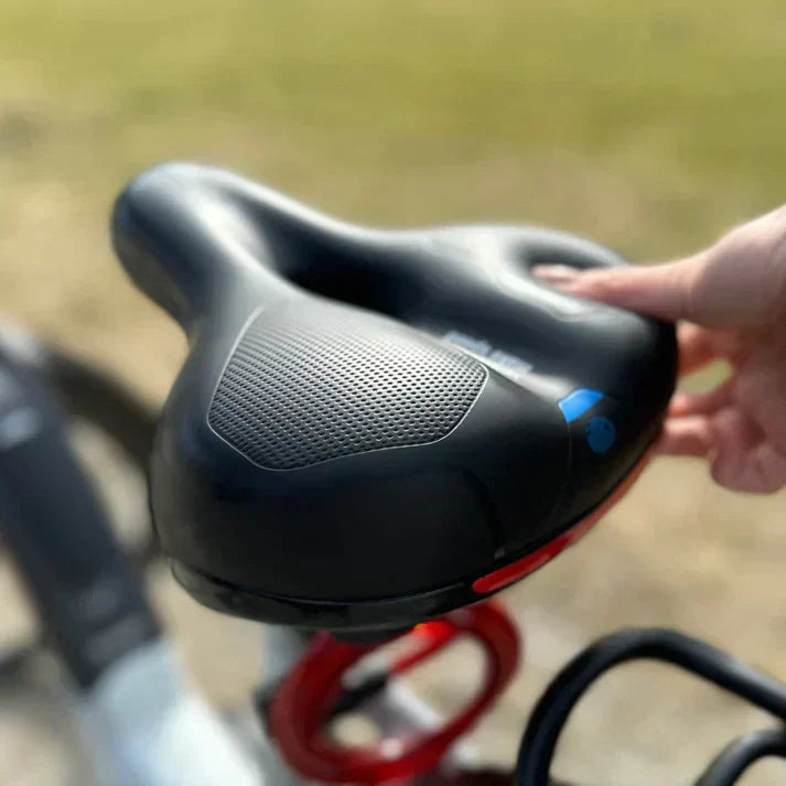 Selle VTT ergonomique rouge, confort et absorption chocs pour sentiers difficiles.