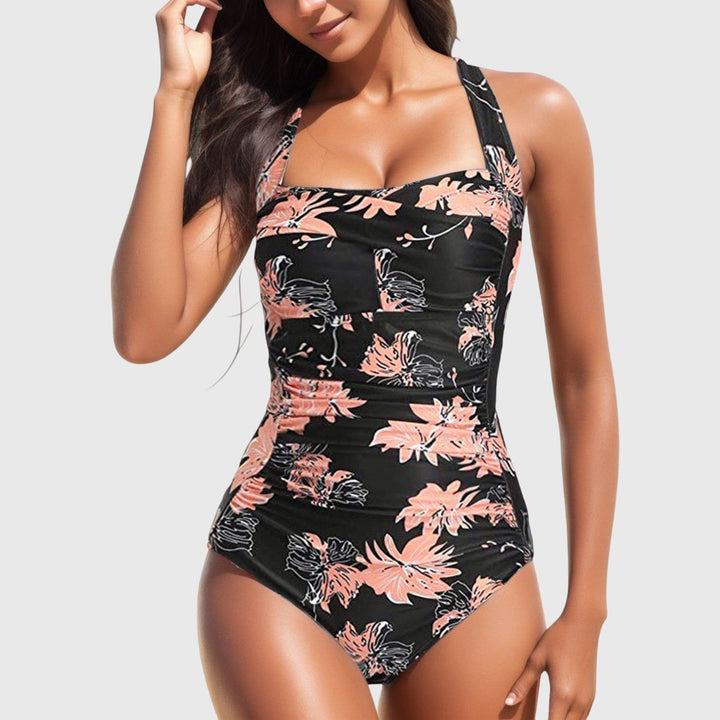 Femme portant un maillot de bain une pièce tropical froncé, col carré, parfait pour l'été en mode plage.