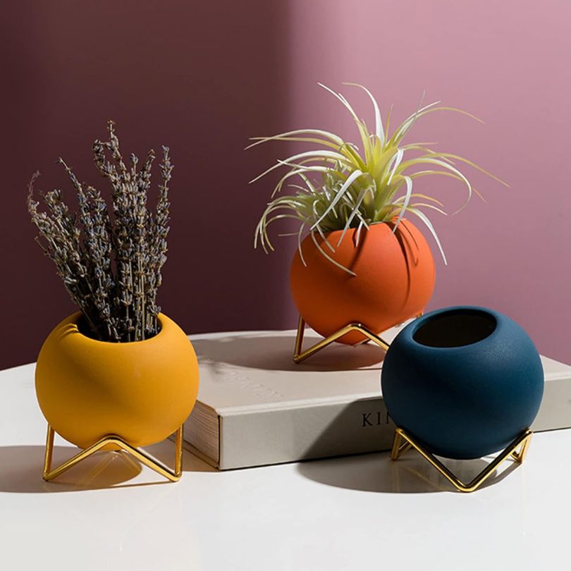 Élégant pot de fleurs en céramique blanche et support métallique noir, design scandinave pour décoration intérieure.