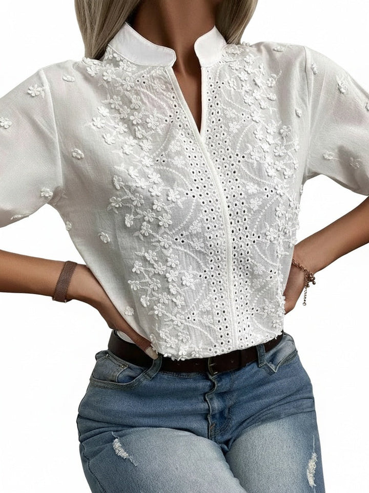 Blouse femme élégante blanche à broderie florale et anglaise, col montant, manches courtes chic.