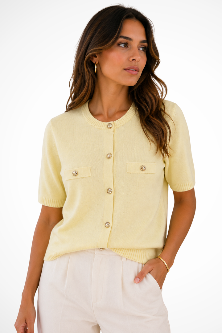 Cardigan femme court et chic, doté de boutons dorés. Idéal pour compléter une tenue élégante ou décontractée estivale.