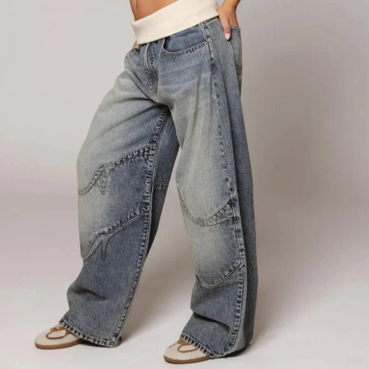 Jean femme taille haute baggy, couleur denim, avec sa ceinture côtelée pour un look urbain et confortable.
