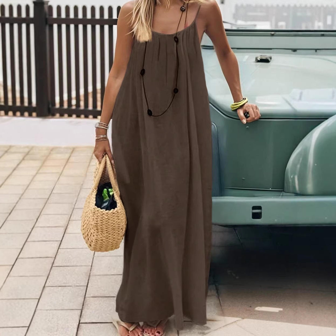 Robe maxi femme de vacances, fluide et sans manches, avec bretelles fines, dos ouvert et poches. Style estival.