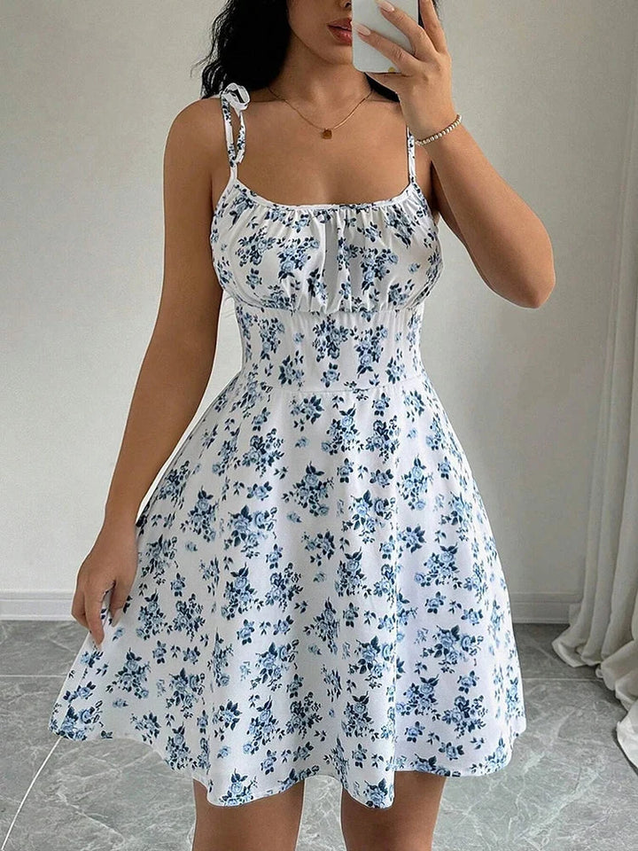 Robe courte femme fleurie, col carré, bretelles nouées. Look féminin et décontracté pour les journées d'été.