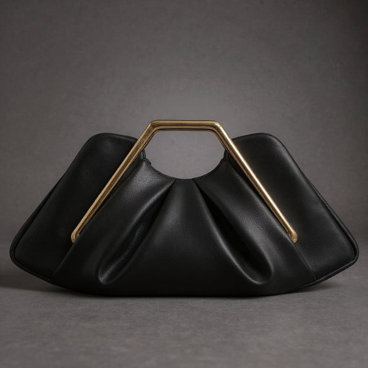 Détail de la poignée dorée sur la pochette de luxe La Courbe femme, design origami cuir et microfibre.
