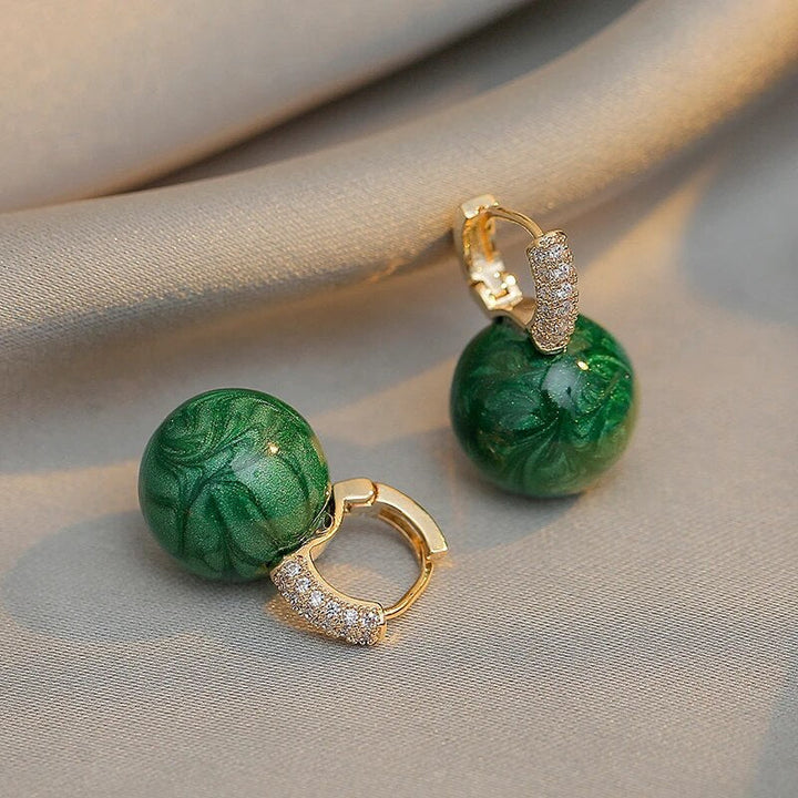 Boucles d'oreilles rondes femme en argent doré, ornées de perles vertes luxueuses.