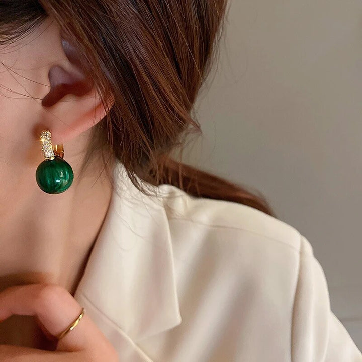 Accessoire féminin: boucles d'oreilles rondes élégantes avec de magnifiques perles vertes.