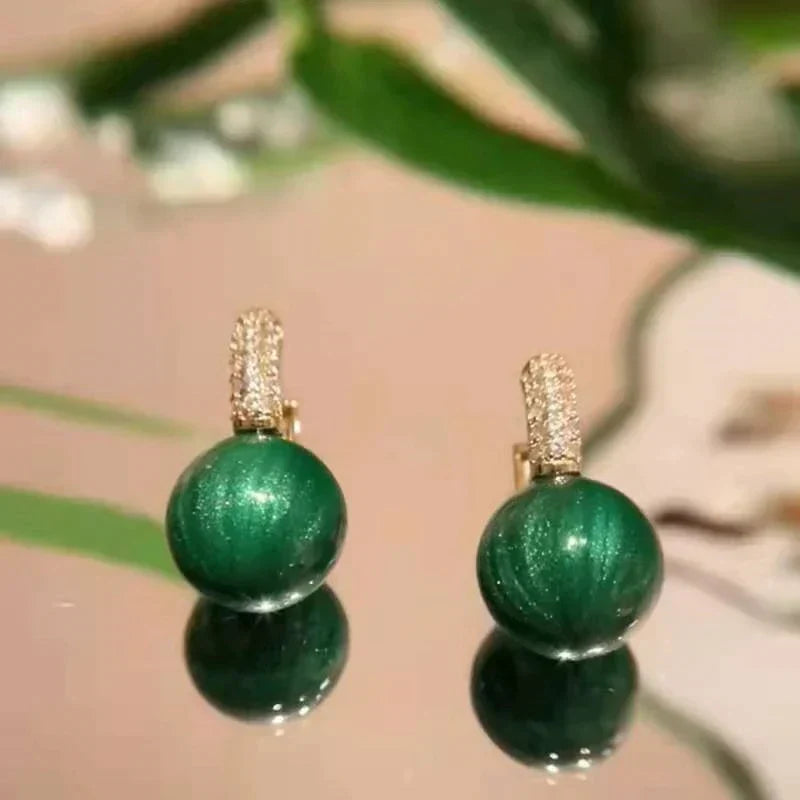Luxueuses boucles d'oreilles rondes pour femmes, perles vertes intenses montées sur argent doré.