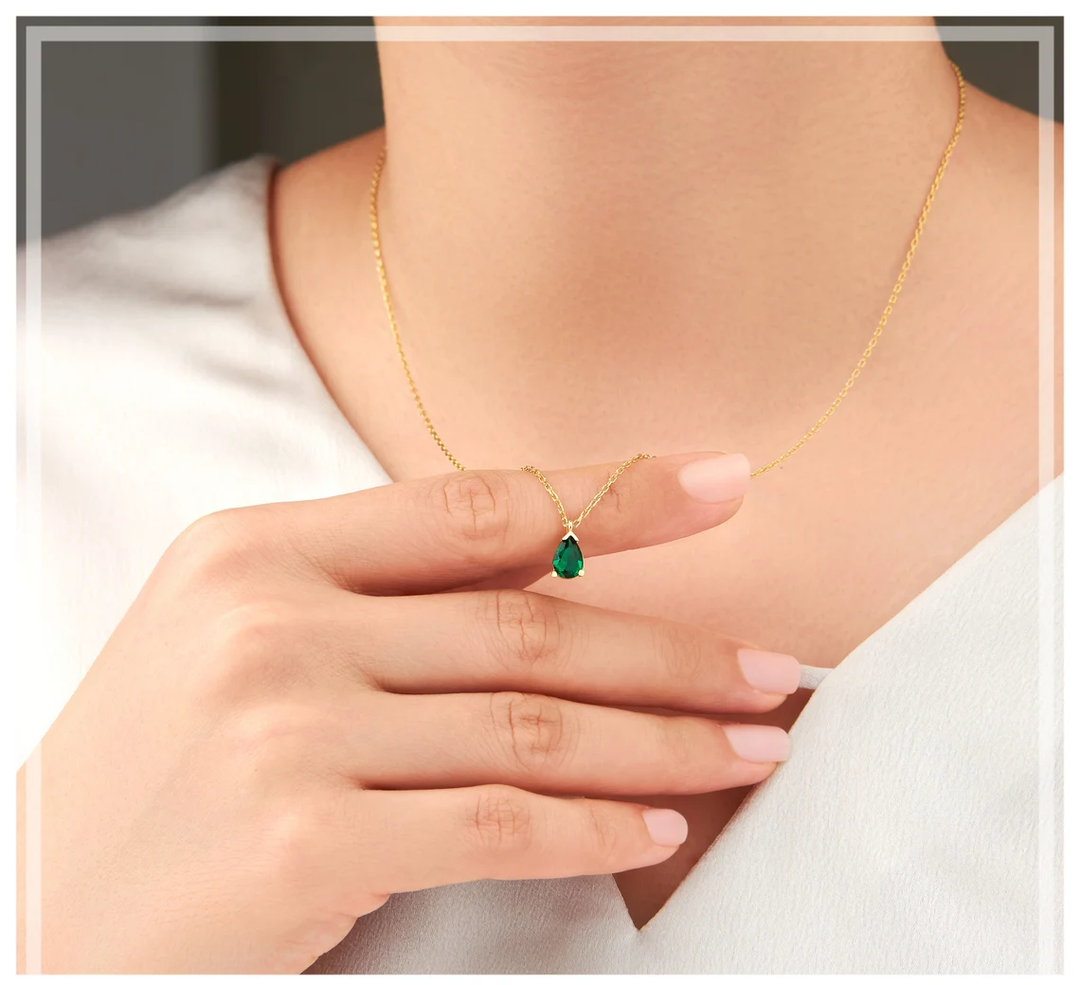 Collier femme élégant avec pendentif goutte d'émeraude scintillante et strass. Bijou précieux pour soirée.