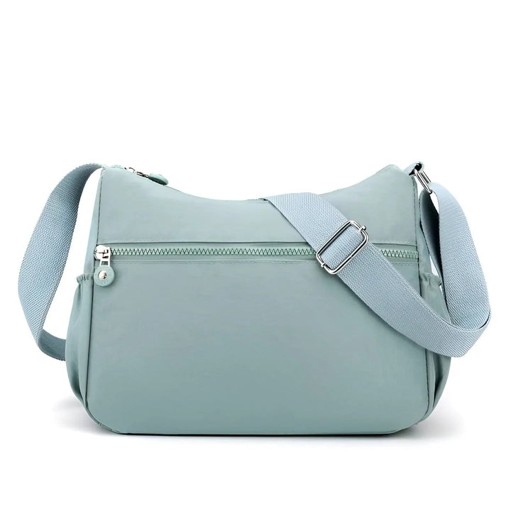 Femme portant un sac à bandoulière noir, imperméable et spacieux, soulignant son élégance et sa praticité.