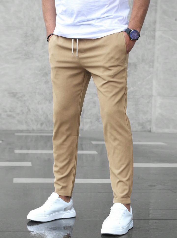 Gros plan sur le cordon de serrage et les revers d'un pantalon chino homme slim moderne.