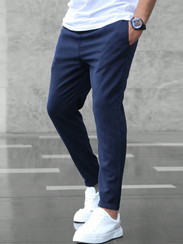 Homme marchant en pantalon chino slim moderne, ceinture élastique et revers stylés.