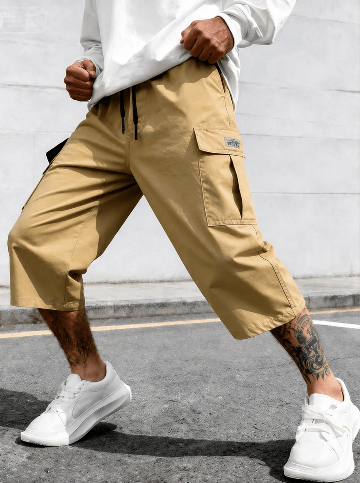 Homme portant un short cargo décontracté, avec poches et cordon de serrage, idéal pour les activités estivales.