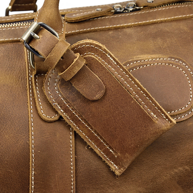 Sac de voyage homme en cuir marron, duffel vintage avec poignées robustes et bandoulière réglable.