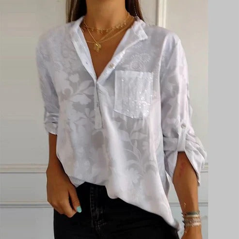 Gros plan sur le tissu fluide de la blouse fleurie femme, motifs floraux détaillés, texture douce.