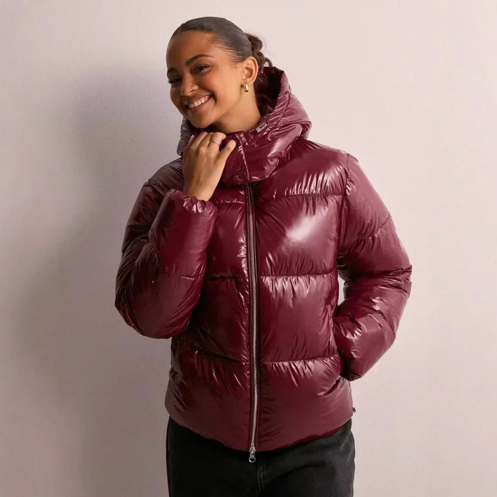 Veste courte brillante femme, style puffer, avec capuche. Chaude et tendance pour l'hiver urbain.