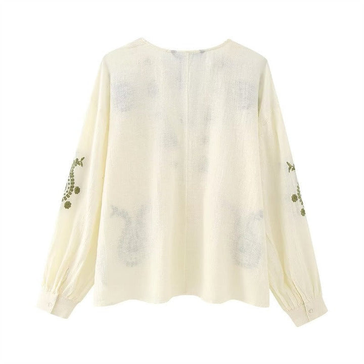 Chemisier femme brodé avec détails raffinés, encolure V, pour un style chic ou décontracté au printemps.