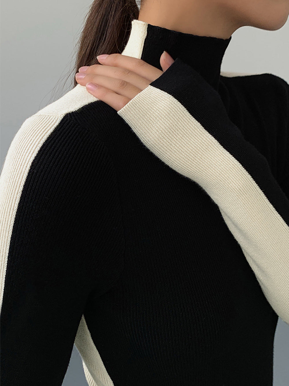 Détail du pull côtelé noir pour femme, col roulé douillet, matière confortable. Idéal pour la mode hivernale élégante.