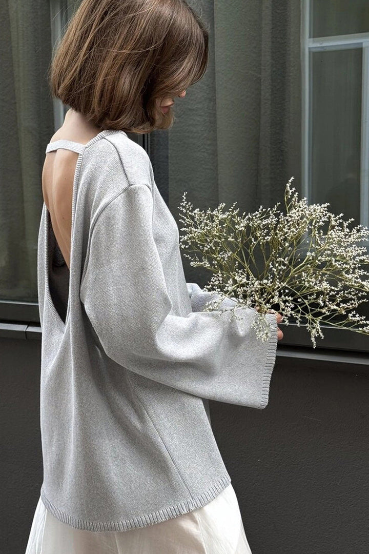 Look mode avec un pull femme oversize gris, son dos nu et ses manches longues, élégant et cosy.